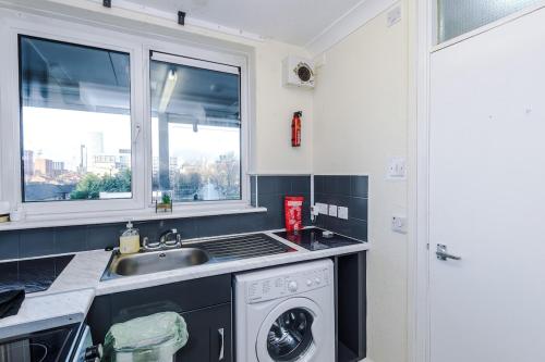 a kitchen with a sink and a washing machine at 1BR Apartment By Kammili Properties - Near City Centre, Universities & Hospital in Manchester