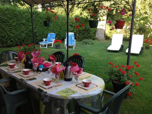 a table with red flowers on it in a garden at Chambre d'Hôtes Quietude en Vallée de Chevreuse in Magny-les-Hameaux