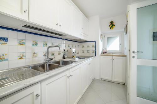 a kitchen with white cabinets and a stainless steel sink at La Dolce Vita Ravello - Exclusive Family & Group Villa with 4 Apartments, 5 Bedrooms in Ravello