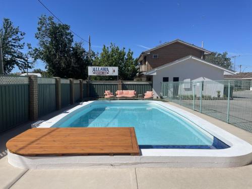 a swimming pool with a wooden table in front of a house at Albury Allawa Motor Inn in Albury