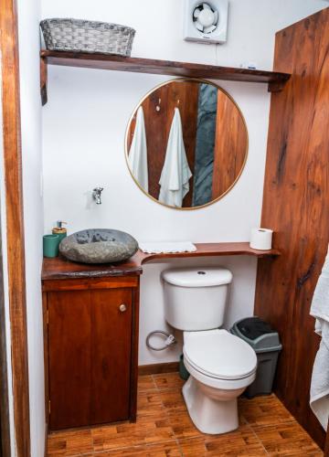 a bathroom with a toilet and a mirror at La Pérgola lodge in Sarapiquí