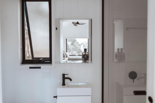 a white bathroom with a sink and a mirror at Tiny Ikigai in Wallan