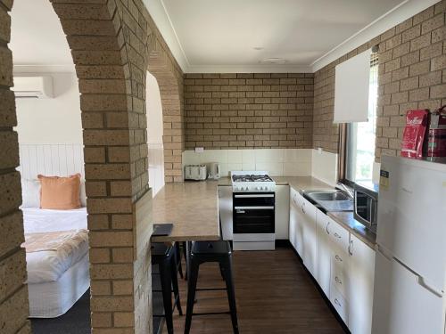 a kitchen with white appliances and a table and a bed at Albury Allawa Motor Inn in Albury