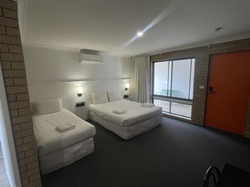 ein Hotelzimmer mit zwei Betten und einem Fenster in der Unterkunft Albury Allawa Motor Inn in Albury