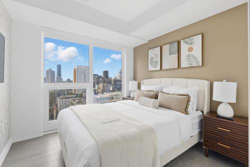 a bedroom with a large white bed and a large window at Modern Downtown Retreat 3BR Condo with Patio in Toronto