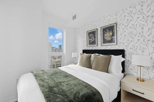 a white bedroom with a bed and a window at Modern Downtown Retreat 3BR Condo with Patio in Toronto