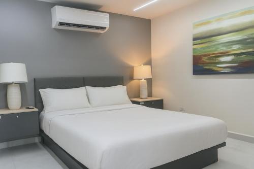 Ocean Park Studio Pool at Riviera Villa في سان خوان: غرفة نوم بسرير ابيض ولوحة