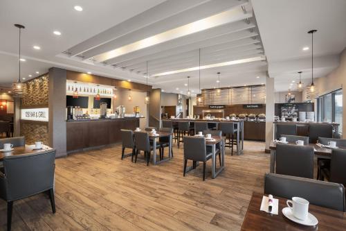 a rendering of a restaurant with tables and chairs at Holiday Inn Calgary Airport by IHG in Calgary