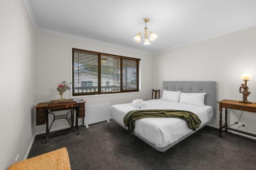 a white bedroom with a bed and a window at Beach Retreat in Warrnambool