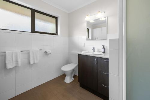 a white bathroom with a sink and a toilet at Beach Retreat in Warrnambool