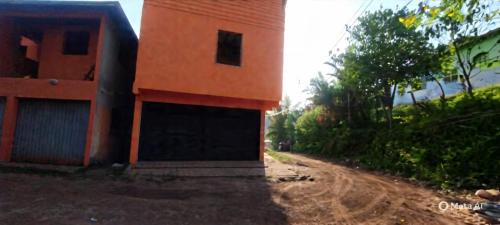 欧鲁普雷图Casa moderna em meio à natureza的土路上一栋带车库的橙色建筑