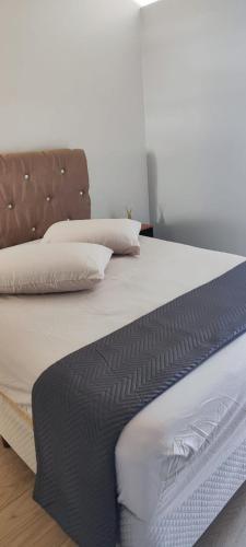 un letto con lenzuola bianche e cuscini sopra di Suite Master Bella a São José