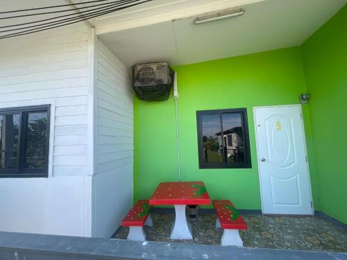 a room with a red table and a green wall at Manee House - บ้านมณี in Buriram