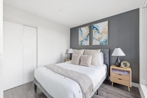 a white bedroom with a large bed and a nightstand at Bright Downtown Condo with City Views & Comfort in Toronto