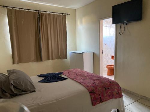 a bedroom with a bed with a television on the wall at Quarto econômico no centro in Sete Lagoas