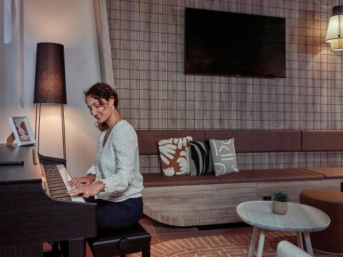 eine Frau, die in einem Wohnzimmer Klavier spielt in der Unterkunft Aparthotel Adagio Original Toulouse Centre La Grave in Toulouse