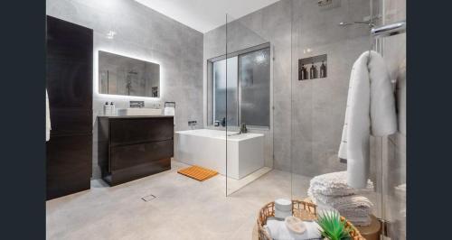 Un baño con ducha, lavabo y bañera. en Serenade Retreat, At Coomera Waters, Gold Coast, en Gold Coast