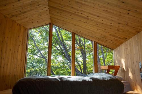 ein Schlafzimmer in einem Baumhaus mit einem großen Fenster in der Unterkunft Earthboat Nasu in Nasu