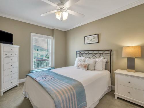 a bedroom with a bed with a ceiling fan and a window at Silver Seas 103 in Tybee Island