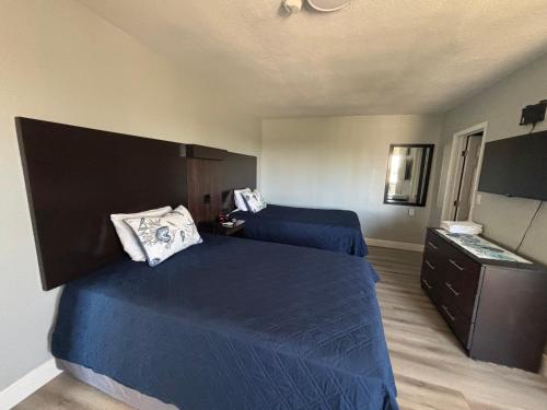 1 dormitorio con 2 camas azules y vestidor en La Bella Oceanfront Inn - Daytona, en Daytona Beach