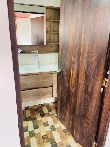 a bathroom with a sink and a wooden door at Cabaña Viento Sereno in Tibaná