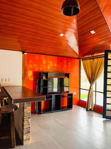 a living room with orange walls and a table at Cabaña Viento Sereno in Tibaná