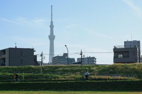 Zwei Personen fahren mit Fahrrädern in einer Stadt mit einem Fernsehturm in der Unterkunft Skytree View Riverside Terrace in Tokio