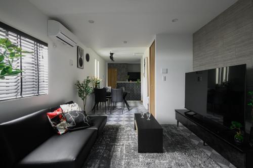 a living room with a black couch and a television at Skytree View Riverside Terrace in Tokyo