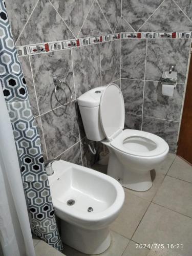 a bathroom with a toilet and a shower curtain at Aguaribay Cabañas in Arroyo de Los Patos