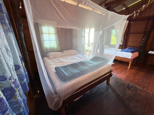 zwei Betten in einem Zimmer mit Moskitonetz in der Unterkunft Ao Siri Beach Bungalow in Ko Jum