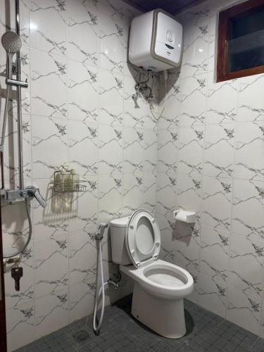 a bathroom with a toilet and a paper dispenser on the wall at Qchen Cuan Cabin Amed in Amed