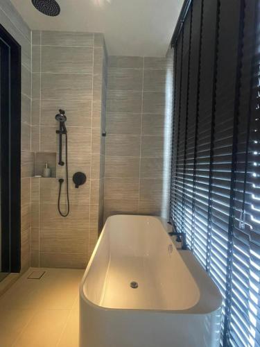 a white bath tub in a bathroom with a shower at Antara Genting by Enigma 2BR, Mid Floor in Genting Highlands