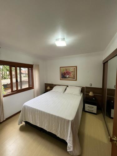 a bedroom with a white bed and a window at Meu cantinho in Canela