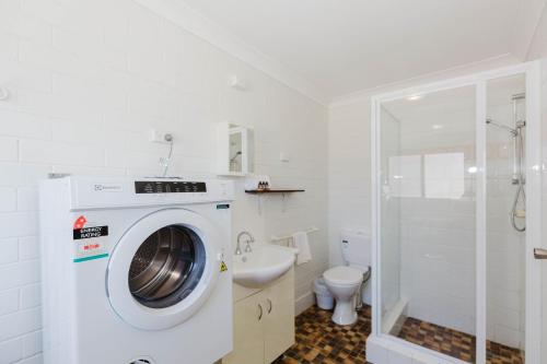 Alpha Centauri - 8 - 39 Gippsland Street في جيندابين: وجود غسالة ملابس في الحمام مع وجود مغسلة ومرحاض