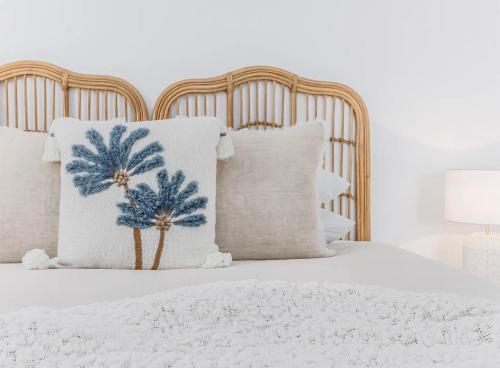 a white bed with white pillows and palm trees on it at The Sand Box in Kingscliff