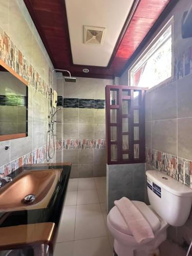 a bathroom with a sink and a toilet and a tub at golden hotel dondet in Don Det