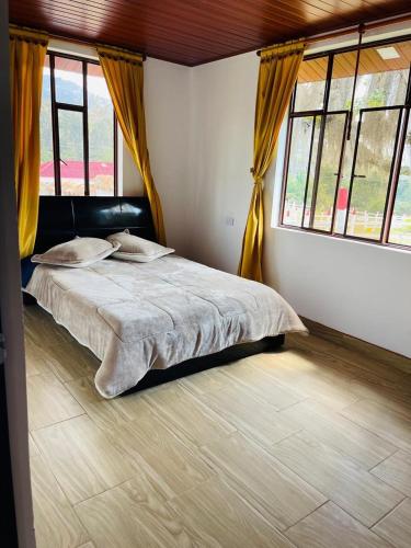 a bedroom with a large bed with yellow curtains at Cabaña Brisa Andina in Tibaná