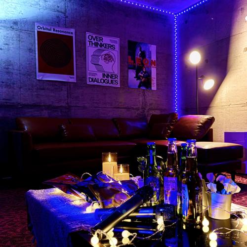 a room with a couch and a table with bottles at Hot spring ,Max 28 ppl, 24 beds, 2 futons, Darts & Karaoke, 2 parking in Yuzawa