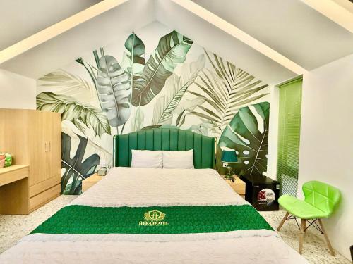 ein Schlafzimmer mit einem grünen Bett und einem Wandbild aus Blättern in der Unterkunft Khách sạn Hera Hotel in Hà Ðông