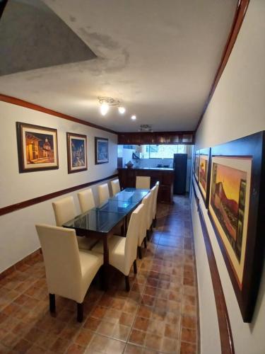 a dining room with a table and white chairs at Hospedaje El Escudero in Trujillo