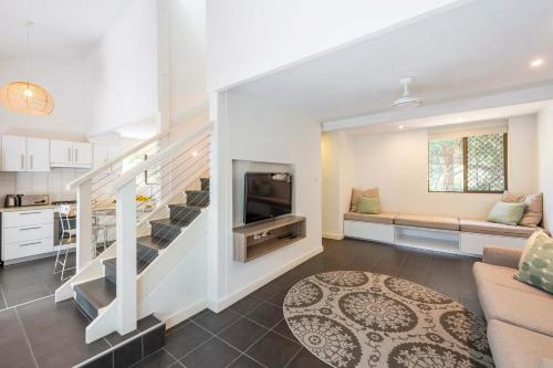 Bayshore Bungalow 12 - Oceanstays في خليج بايرون: غرفة معيشة مع أريكة وتلفزيون ومطبخ