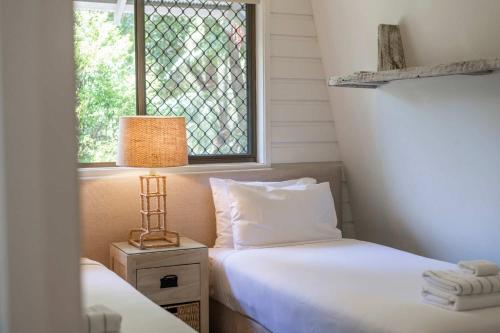 Bayshore Bungalow 12 - Oceanstays في خليج بايرون: غرفة نوم بسريرين ومصباح ونافذة