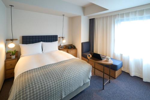 a hotel room with a bed and a laptop on a table at Hotel Resol Stay Akihabara in Tokyo