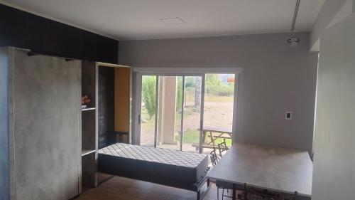Una habitación con una cama y una puerta corrediza de vidrio. en Preciosa Casa con Terraza al Valle Grande, San Rafael Mendoza de 1 a 5 Personas, en Valle Grande