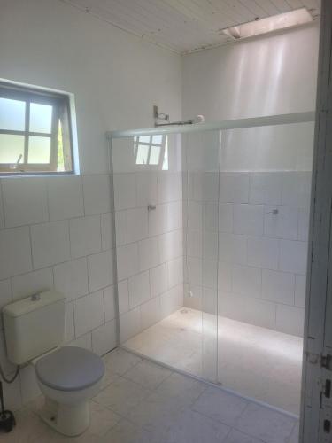 a bathroom with a toilet and a glass shower at Beach house in Pontal do Paraná