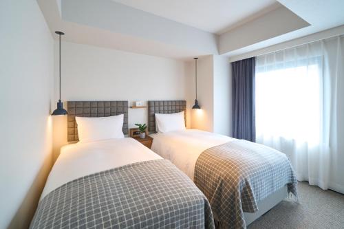 two beds in a room with a window at Hotel Resol Stay Akihabara in Tokyo