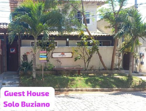 a guest house with a bench and palm trees at Solo Buziano Guest House in Búzios