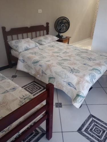a bedroom with two beds and a table with a fan at Casa da alegria in Ubatuba