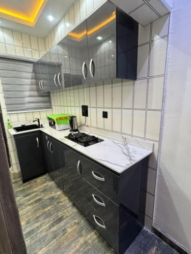 a kitchen with black cabinets and white tile walls at Wii Apartments and Suites in Mama