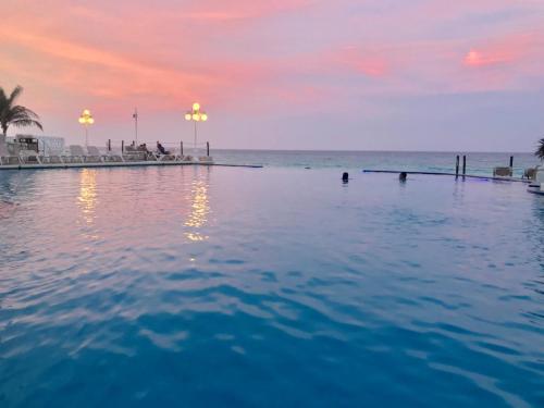 a swimming pool at the beach at sunset at Beach and Ocean Front Apartments Cancun in Cancún